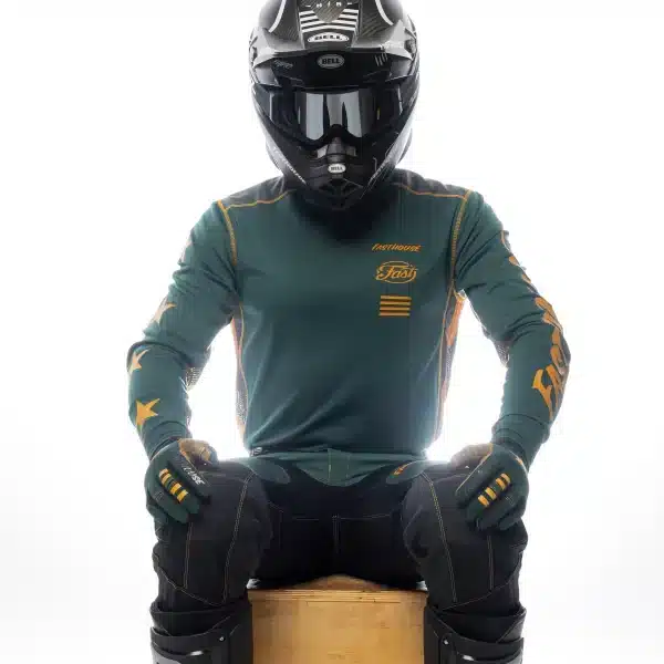 תקריב על בד Micro Mesh נושם ותפרים שטוחים לוגו Fasthouse על החזה בעיצוב Grindhouse